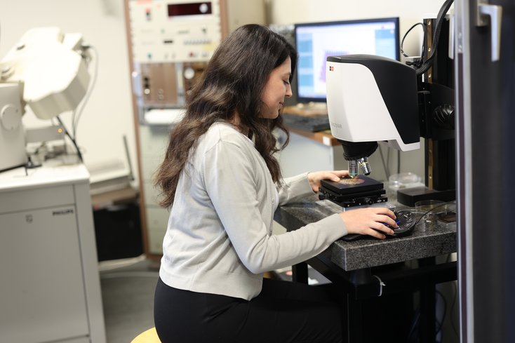 Studentin untersucht etwas unterm Mikroskop.