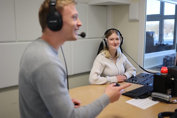 Ein Student und eine Studentin im Radiostudio mit Headsets und Mischpult