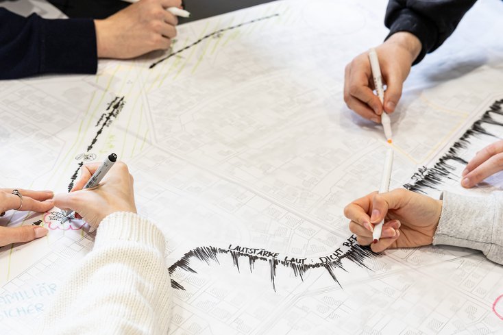 Hände zeichnen auf einer Stadtkarte etwas ein