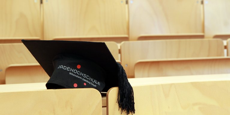 Doktorhut liegt auf einem Tisch in einem Hörsaal.
