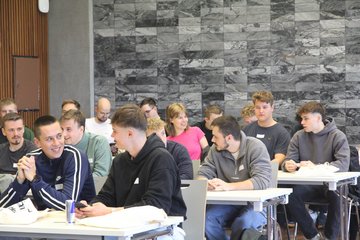 Erstsemester sitzen an Tischen und unterhalten sich.