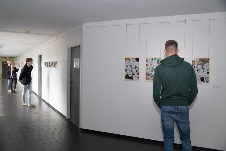 Studierende betrachten die Ausstellung. Im Bild vorne zu sehen ist die Serie „Auf den zweiten Blick“ zum Jade Wert „vielfältig“. (Foto: Geert Oeser/Jade HS)