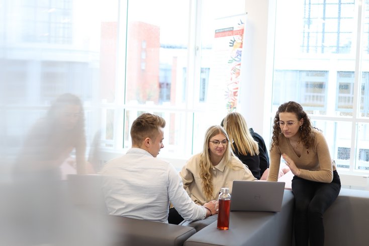Gruppe von Studierenden bespricht etwas am Laptop.