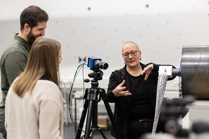 Drei Personen befinden sich im Mess-Labor und tauschen sich aus.