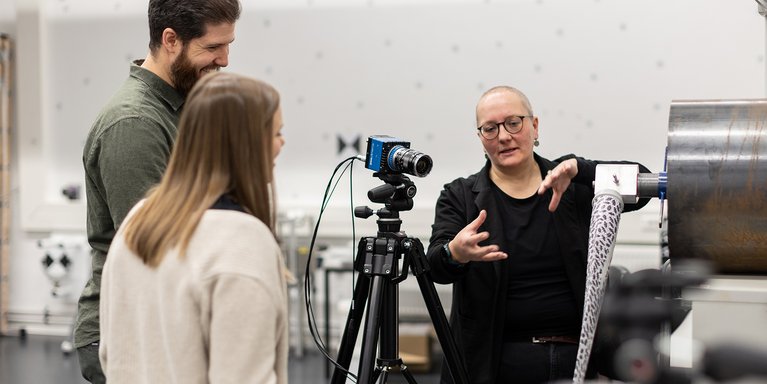 Drei Personen befinden sich im Mess-Labor und tauschen sich aus.