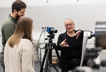 Drei Personen befinden sich im Mess-Labor und tauschen sich aus.