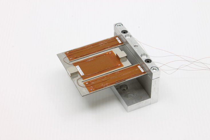 Mit einem im Maßstab 100 000:1 vergrößerten Modell überprüft das Projektteam, ob der automatisiert entworfene Energiewandler wie gewünscht funktioniert. Besteht das Modell diesen Test, wird schließlich ein Prototyp im echten miniaturisierten Maßstab erstellt. Das aufgebrachte braun gefärbte Material beim Modell-Demonstrator erzeugt bei Verformung oder Druck elektrische Ladung. Foto: Jade Hochschule/Projekt optiMUM