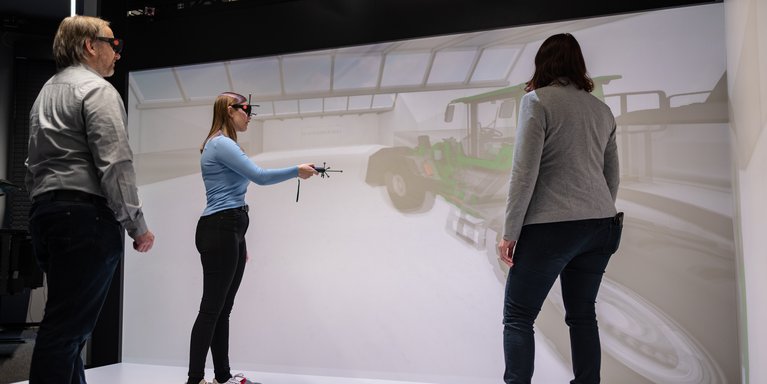 Studierende demonstriert zwei Dozierenden etwas im Virtual Reality Raum.
