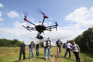 Mehrere Personen lassen Drohne für eine Vermessung fliegen