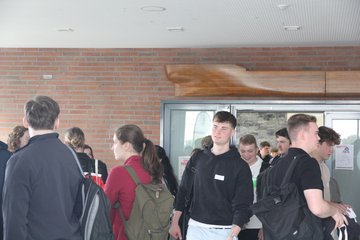 Zahlreiche Erstsemesterstudierende verlassen gut gelaunt die Aula und unterhalten sich im Foyer.