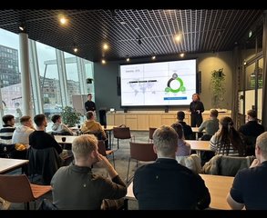 Studierende sitzen in einem Raum der Firma Deloitte und sehen sich eine Präsentation an.