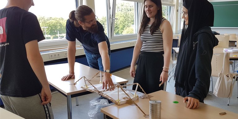 Schüler_innen testen die Tragfähigkeit einer selbst gebauten Brücke beim Workshop zum Thema "Leichtbau" (Foto: Anka Albrecht)