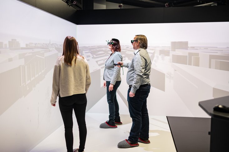 Drei Personen stehen in einem Virtual Reality Raum und demonstrieren etwas.