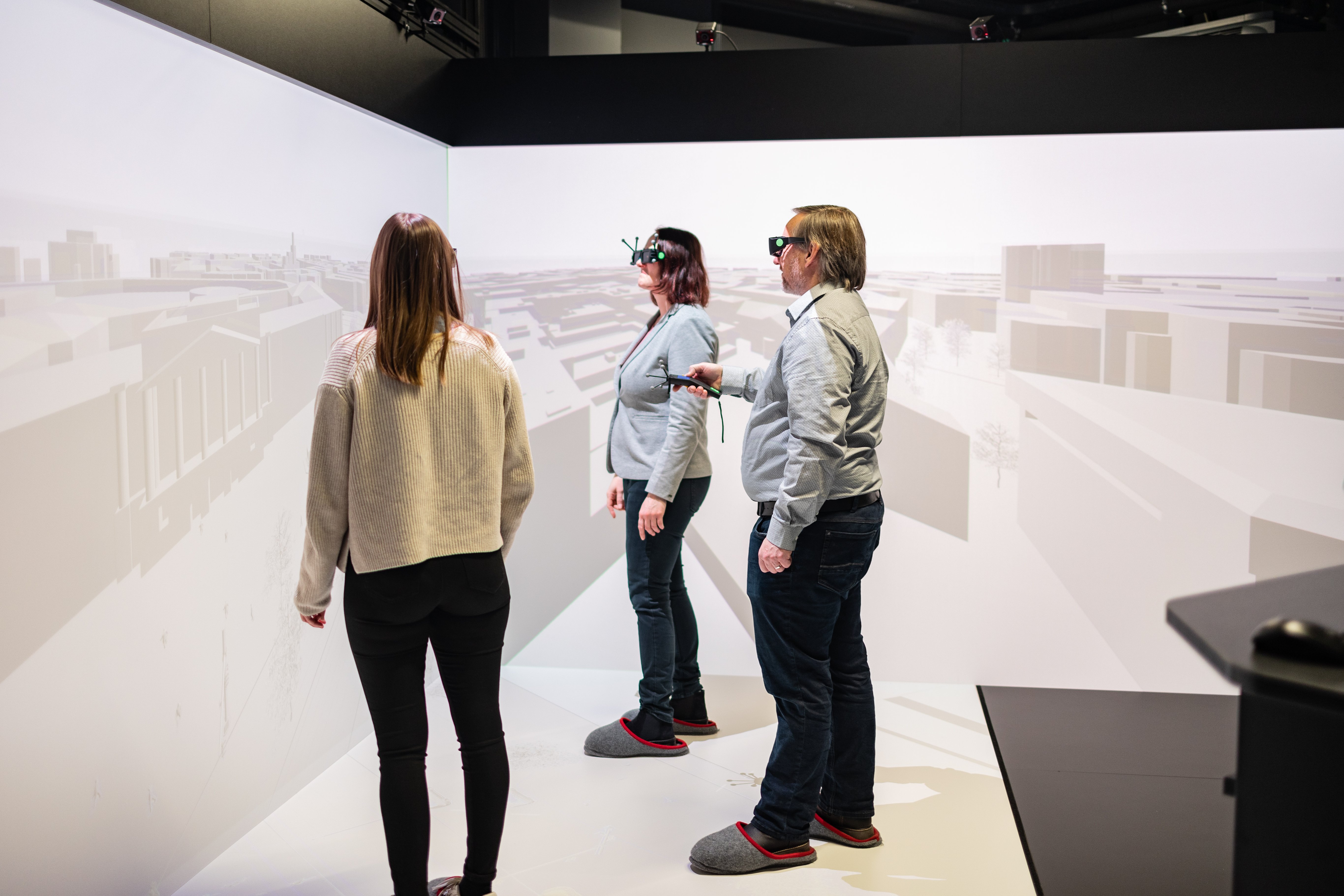 Drei Personen stehen in einem Virtual Reality Raum und demonstrieren etwas.