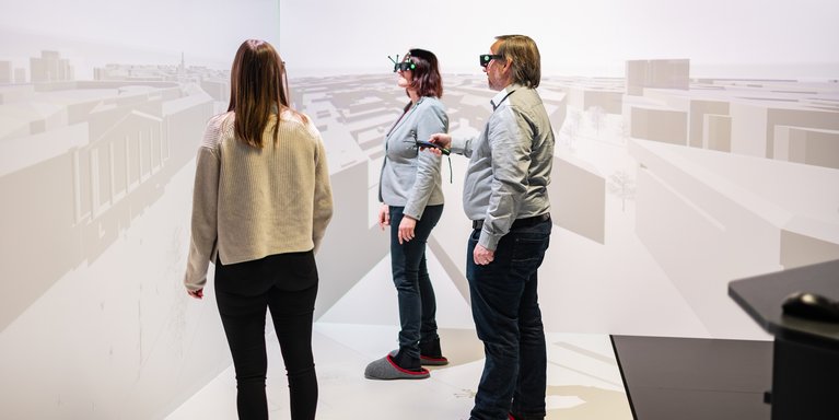 Drei Personen stehen in einem Virtual Reality Raum und demonstrieren etwas.