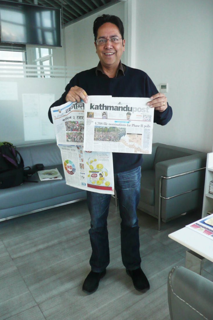 Ein Journalist aus Nepal mit einer nepalesischen und einer englischsprachigen Ausgabe der Kathmandu Post. Für die Ausgaben gibt es separate Redaktionen.