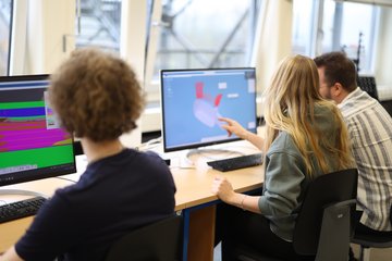 Studierende diskutieren am Rechner.