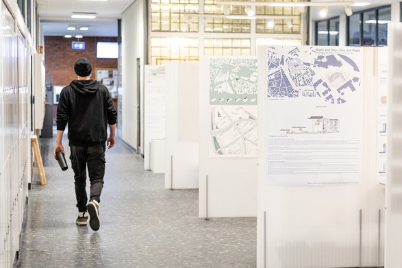Ein Student geht einen Flur entlang mit einer Architekturausstellung
