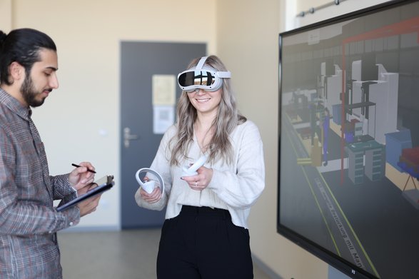 Studentin benutzt eine Virtual Reality Brille und Student macht Notizen auf einem Tablet.