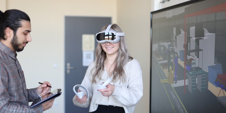 Studentin benutzt eine Virtual Reality Brille und Student macht Notizen auf einem Tablet.