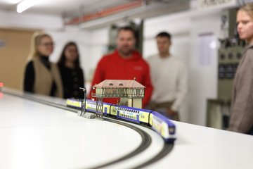 Studierende und Dozent führen Übung im Eisenbahnlabor durch.
