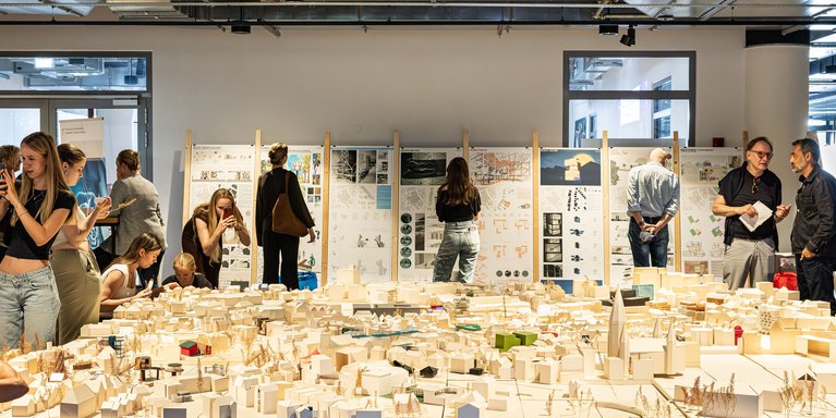 Eine Architekturausstellung mit einem großen Stadtmodell und Besuchern