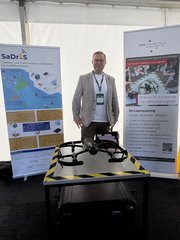 Ein Mitarbeiter steht auf dem Messestand.