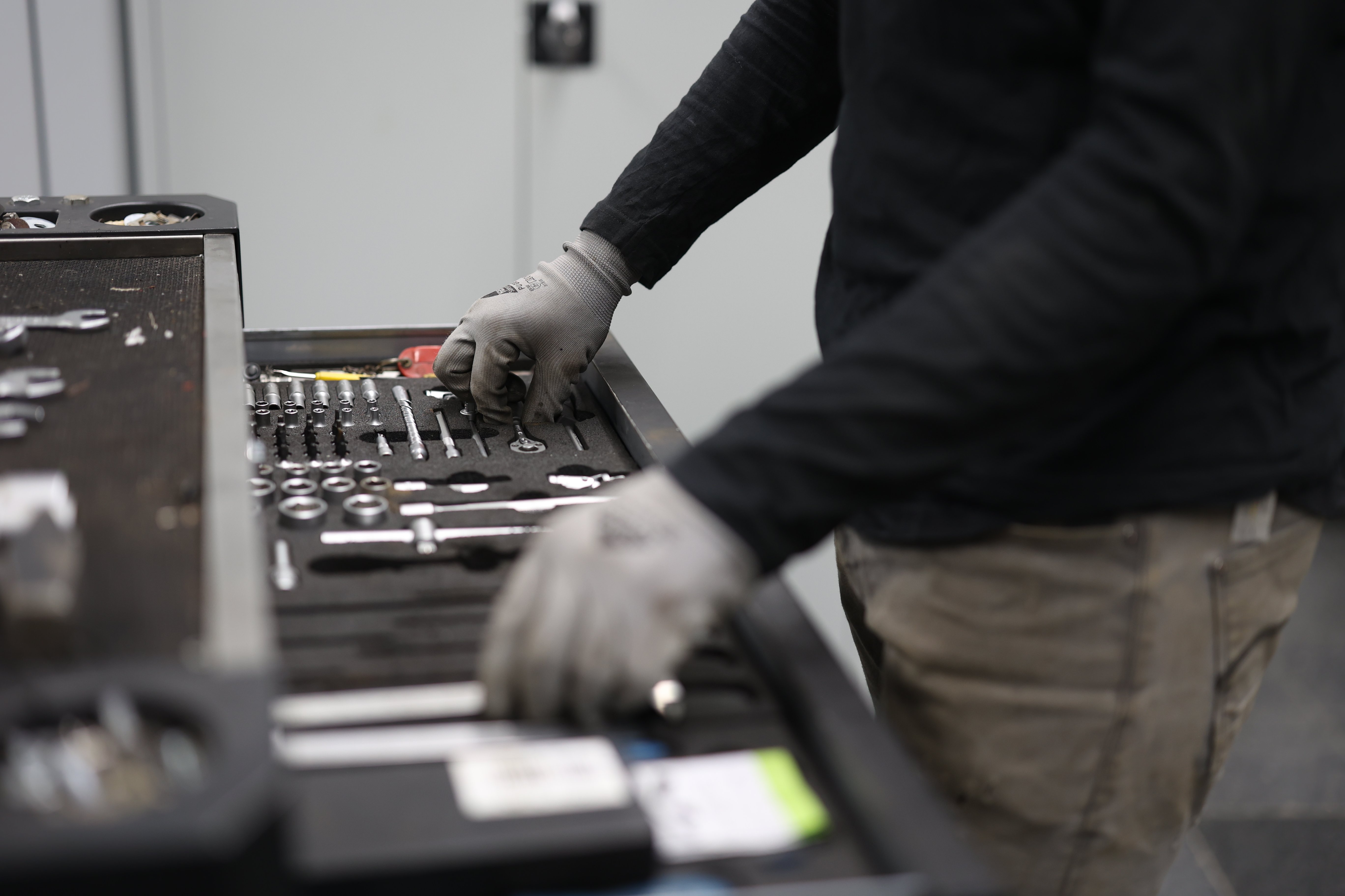 Zwei Hände am Werkzeugkoffer.