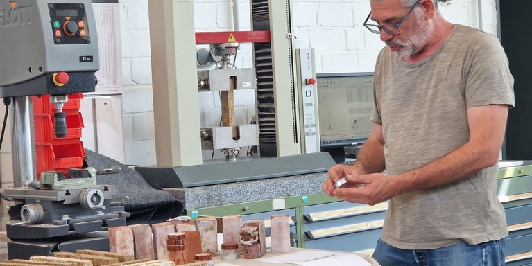 Florian Schick (Mitarbeiter im RoNNi-Projekt) erläutert den Teilnehmenden das Vorgehen bei Materialuntersuchung zur Bestimmung der feuchte-technischen Eigenschaften (Foto: Wibke Baumgarten) 