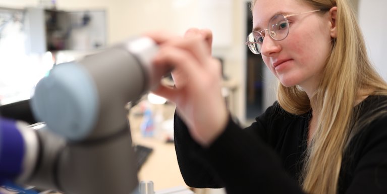 Studentin schraubt am Roboterarm