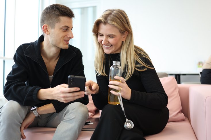 Ein Student erklärt seiner Kommilitonin etwas am Smartphone.