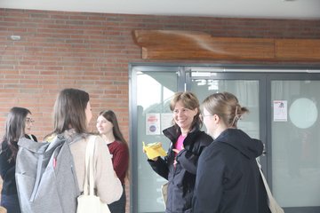 Erstsemesterstudierende stehen zusammen, unterhalten sich und essen dabei Brötchen.