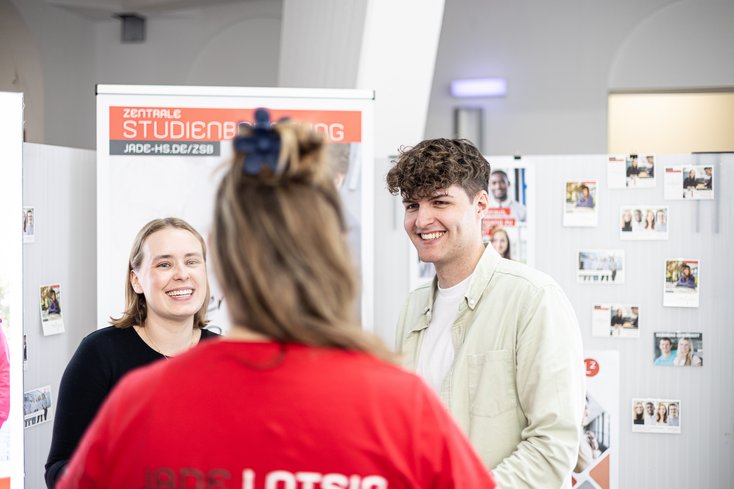 Zwei Personen im Gespräch mit einer Mitarbeiterin der Hochschule