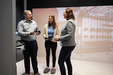 Drei Personen stehen in einem Virtual Reality Raum und diskutieren.