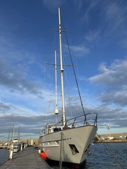 Weißes Segelschiff liegt an einem Holzsteg im Hafen