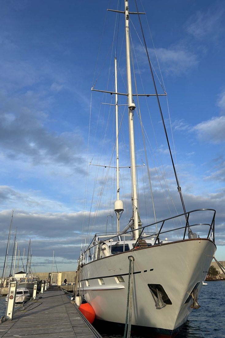 Weißes Segelschiff liegt an einem Holzsteg im Hafen