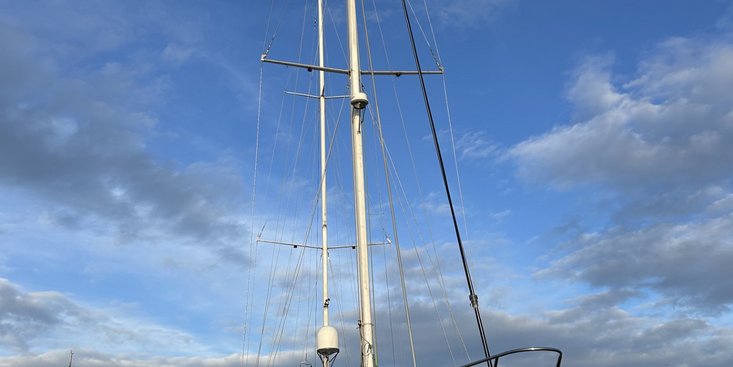 Weißes Segelschiff liegt an einem Holzsteg im Hafen