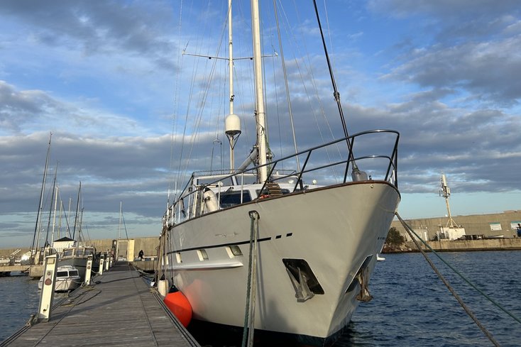 Weißes Segelschiff liegt an einem Holzsteg im Hafen