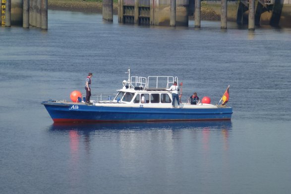 Blaues Motorboot auf dem Wasser, auf dem 4 Studierende arbeiten.