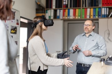 Dozent erklärt Studentin etwas, während sie eine Virtual Reality (VR) Brille auf hat.