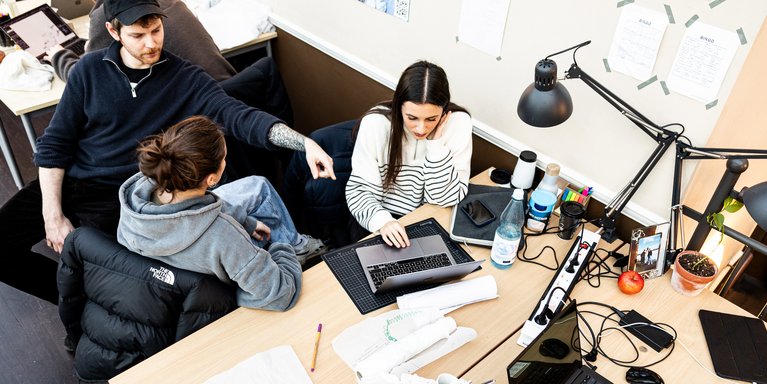 Drei Studierende des Studienganges Urban Design der Jade Hochschule sitzen am Arbeitstisch an einem Laptop und diskutieren