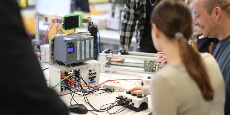 Dozent und Studierende erarbeiten etwas in einem technischen Labor.