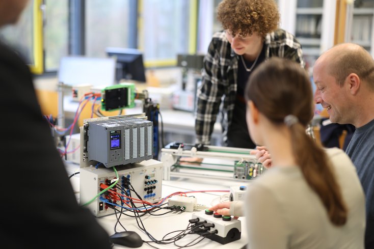 Dozent und Studierende erarbeiten etwas in einem technischen Labor.