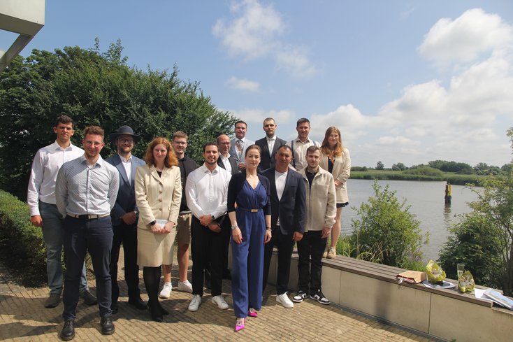 Gruppenfoto der Absolventen des Fachbereichs Seefahrt und Logistik auf der Terrasse des Hauptgebäudes. Im Hintergrund ist die Hunte zu sehen. 