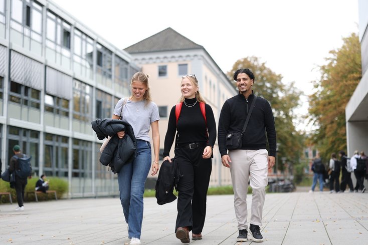 Drei Studierende gehen über den Campus