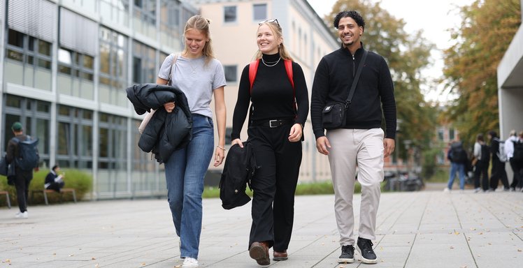 Drei Studierende gehen über den Campus