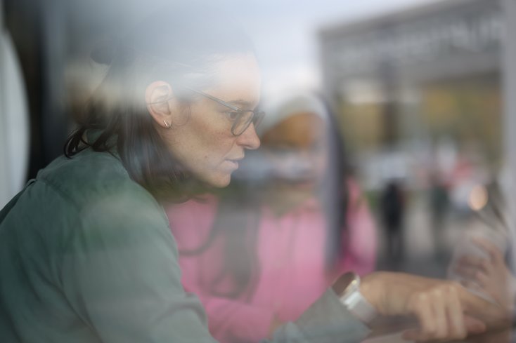Zwei Frauen im Profil sind vor einem Bildschirm in ein Gespräch vertieft.
