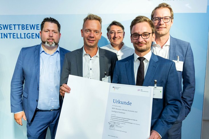 Die Projektpartner des Forschungsprojektes REIF nehmen die Urkunde entgegen (v.l.n.r.): Daniel Schaten (Westfleisch SCE mbH), Tobias Voigt (TU München), Prof. Dr.-Ing. Hergen Pargmann (Jade Hochschule), Alexander Zipfel (Fraunhofer IGCV), Prof. Dr.-Ing. Harald Schallner (Jade Hochschule), Copyright: BMWi/Bildkraftwerk Kurc.