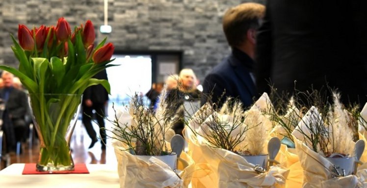 im Vordergrund stehen Geschenke und eine Vase mit roten Tulpen auf einem Tisch