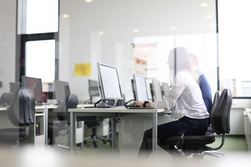Zwei Studierende sitzen an Computern in einem EDV-Raum.